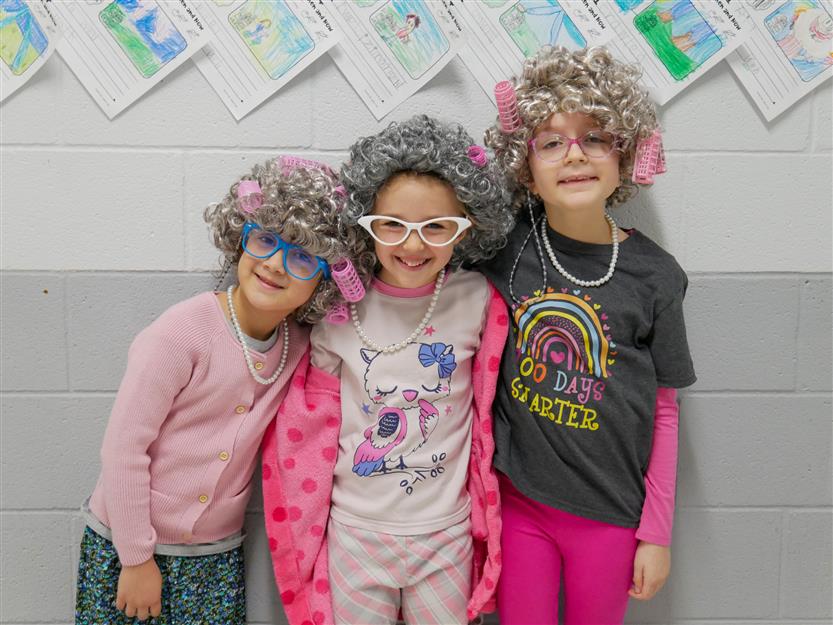 three girls in pink outfits with gray wigs and glasses